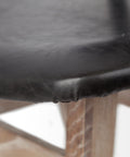 Close-up of a black leather chair seat with a blurred background