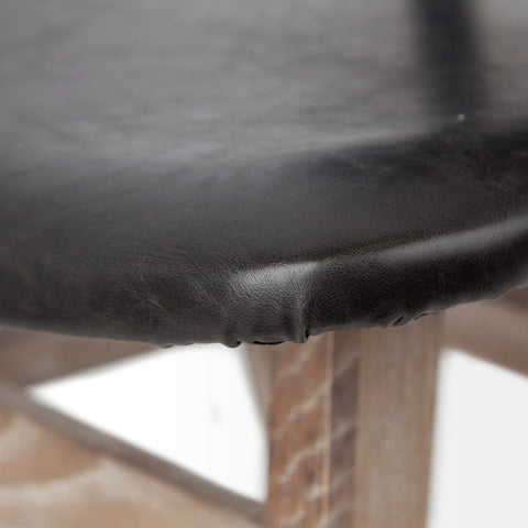 Close-up of a black leather chair seat with a blurred background