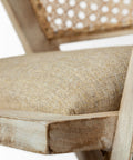 Close-up of a wooden chair with a woven backrest and textured cushion.