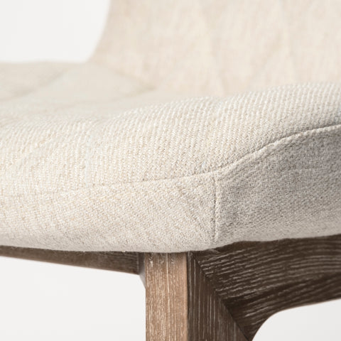 Close-up of a chair with a textured beige cushion and wooden legs on a white background
