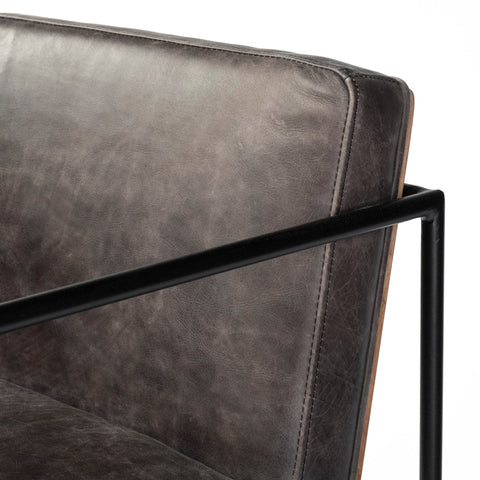 Close-up of a gray upholstered chair with black metal frame on a white background