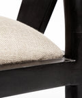 Close-up of a chair with a black frame and beige cushion on a white background