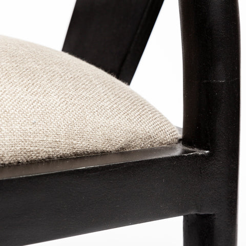 Close-up of a chair with a black frame and beige cushion on a white background
