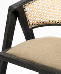 Close-up of a chair with black frame, beige woven backrest, and beige cushion on a white background