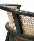Close-up of a chair with black frame and woven backrest on a white background