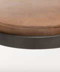 Close-up of a brown leather stool with a metal base on a white background