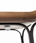 Close-up of a chair with a brown seat and black metal legs on a white background