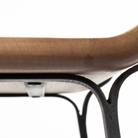 Close-up of a chair with a brown seat and black metal legs on a white background