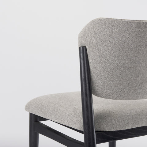 Gray upholstered chair with black metal frame on a light gray background