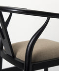 Close-up of a chair with black metal frame and beige cushion on a white background
