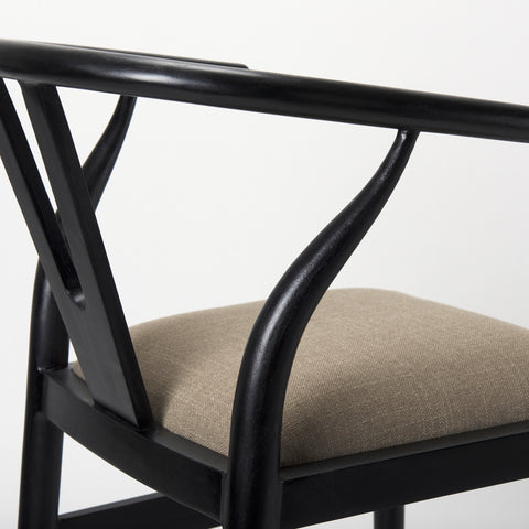 Close-up of a chair with black metal frame and beige cushion on a white background