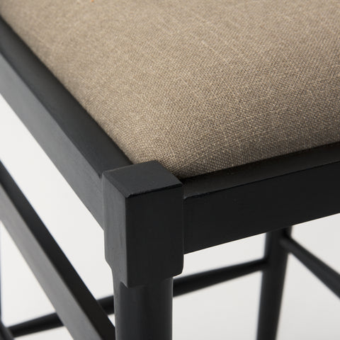 Close-up of a chair with a black frame and beige cushioned seat on a white background