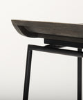 Close-up of a modern chair with a wooden seat and black metal frame on a light gray background