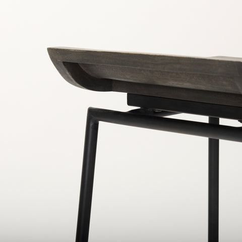 Close-up of a modern chair with a wooden seat and black metal frame on a light gray background