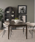 Dining room with a wooden table and chairs, bookshelf, and wall art.