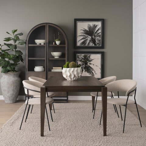 Dining room with a wooden table and chairs, bookshelf, and wall art.