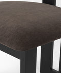 Close-up of a brown upholstered chair seat with black legs on a white background