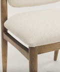 Close-up of a wooden chair with beige cushioned seat and backrest on a light background