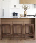 Modern kitchen with wooden island and stools, white cabinets, and decorative items.