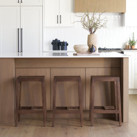 Modern kitchen with wooden island and stools, white cabinets, and decorative items.
