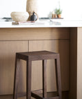 Wooden bar stool in front of a kitchen counter with a marble top.