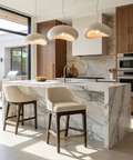 Modern kitchen with marble island, wooden cabinets, and pendant lights.