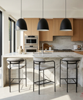 Modern kitchen with marble island, wooden cabinets, and black pendant lights.