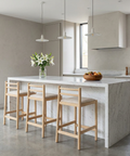 Modern kitchen with a marble island and wooden stools.
