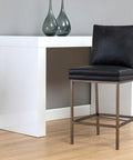 Black bar stool in front of a white counter against a gray wall.