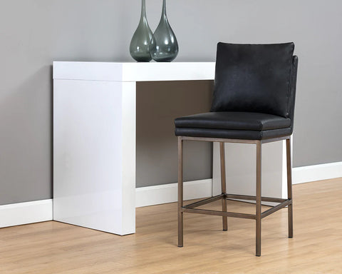 Black bar stool in front of a white counter against a gray wall.