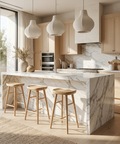 Modern kitchen with marble island, wooden stools, and natural light