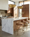 Modern kitchen with marble island, wooden cabinets, and gold accents.