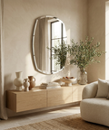Modern living room with a wooden console table, round mirror, and decorative items.