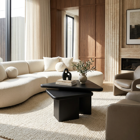 Modern living room with a beige sectional sofa, black coffee table, and decorative items.
