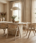 Dining room with wooden table and chairs, large windows, and decorative elements.