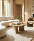 Modern living room with beige sofa, round wooden coffee table, and armchair.
