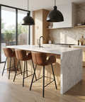 Modern kitchen with marble island, bar stools, and stainless steel appliances.