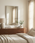 Neatly arranged bedroom with wooden dresser, mirror, and bed.
