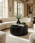 Modern living room with a black round coffee table, white sofa, and decorative elements.