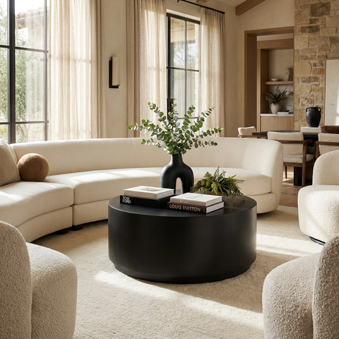 Modern living room with a black round coffee table, white sofa, and decorative elements.