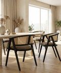 Modern dining room with wooden table and black chairs, large windows, and neutral decor.