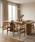 Dining room with wooden table and chairs in a bright room with large windows.