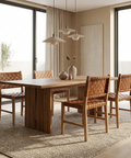 Dining room with wooden table and chairs near large windows.