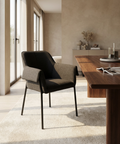 Modern chair in a stylish room with a wooden table and large windows.