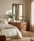 Neatly arranged bedroom with wooden dresser, mirror, and decor items.