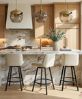 Modern kitchen with marble island, bar stools, and pendant lights.