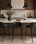 Modern kitchen with marble island, black bar stools, and pendant lights.