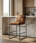 Brown leather bar stool in a modern kitchen with marble countertop and wooden cabinets.