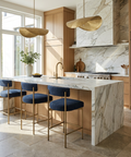 Modern kitchen with marble island, wooden cabinets, and blue stools.