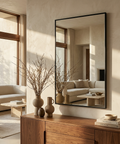 Modern living room with a large mirror, wooden console table, and decorative items.